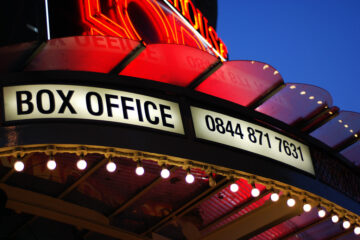 Hell erleuchtetes Gebäude mit beleuchteter "Box Office" Aufschrift bei Nacht