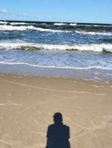 Mein Newsletter Strand mit Meer und als Schatten ist die Silhouette von Ron Vollandt zu sehen