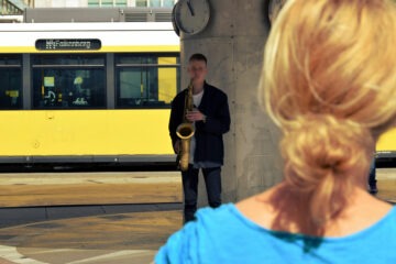 Saxophonist spielt vor einer gelben Berliner Straßenbahn