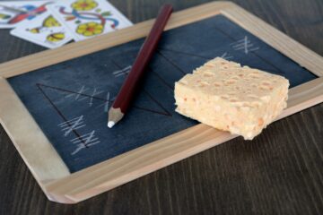 Eine Strichliste auf einer Tafel, die jeden Einzelfall zählt. Darauf liegt ein Schwamm und ein Bleistift.
